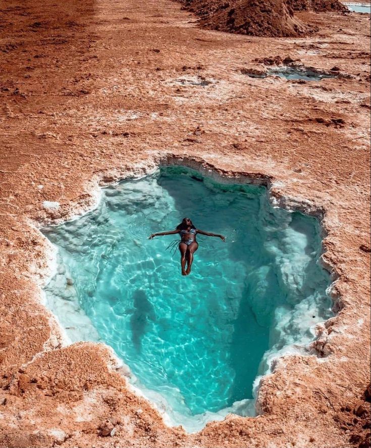 a person jumping into a pool of water in the middle of some dirt and mud