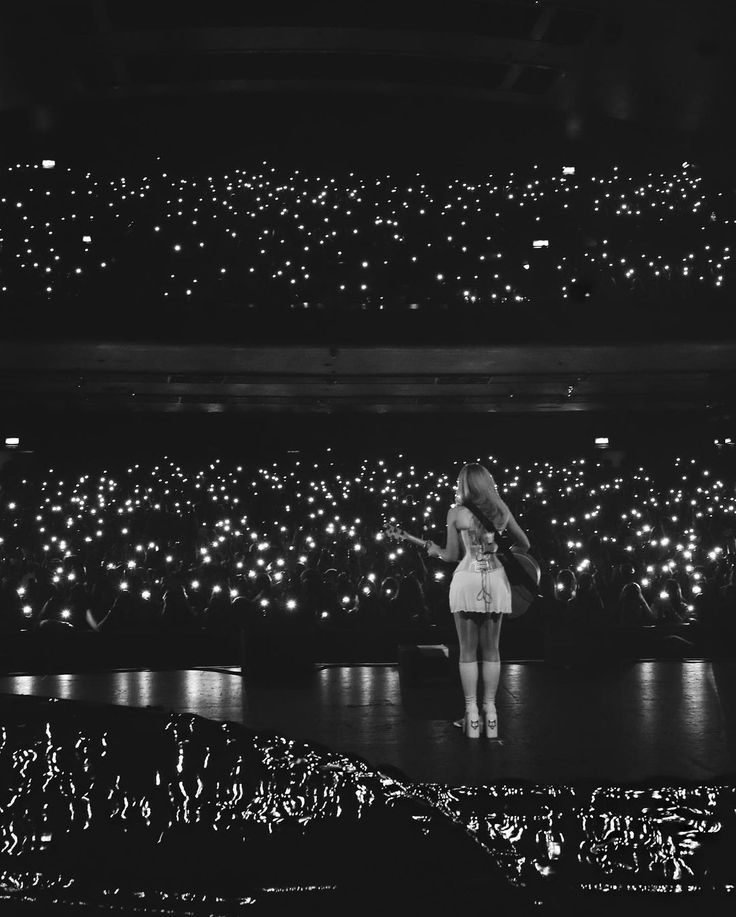 a black and white photo of a woman on stage with lights in the air behind her