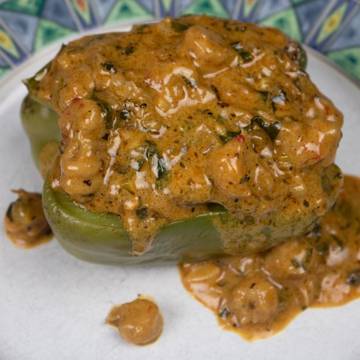 a stuffed pepper covered in sauce on top of a white plate