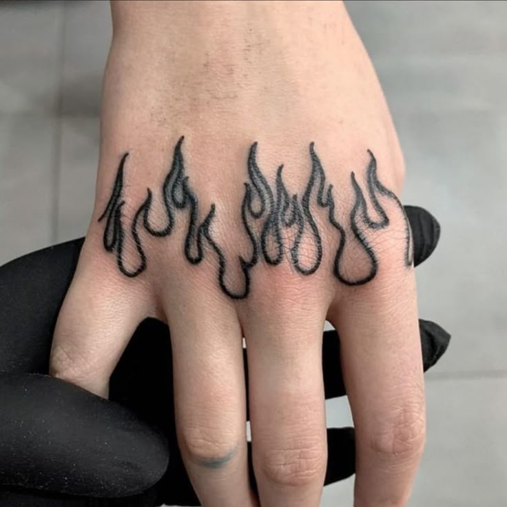 a person's hand with black ink on it and flames coming out of the fingers