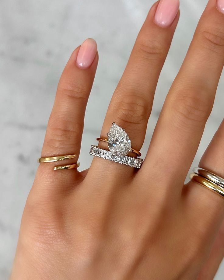 a woman's hand with three different rings on her fingers and one ring in the middle