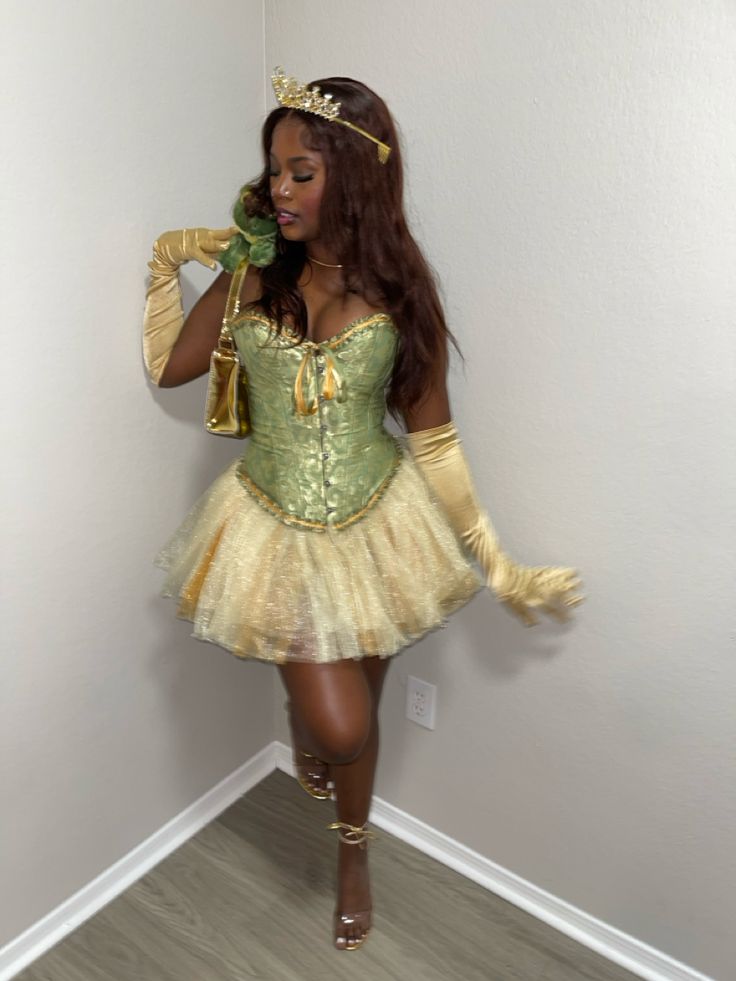 a woman in a green and gold costume is talking on her cell phone while standing against a wall