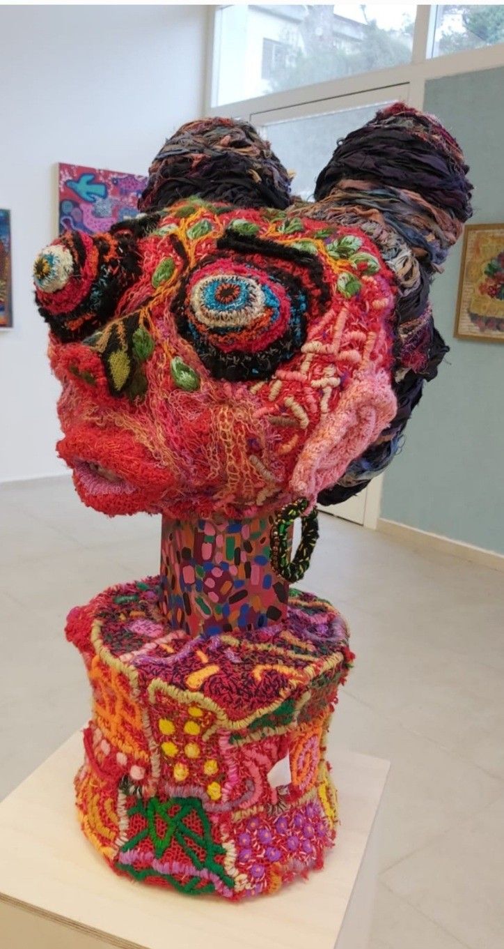 a sculpture made out of different colored yarns on display in a room with white walls