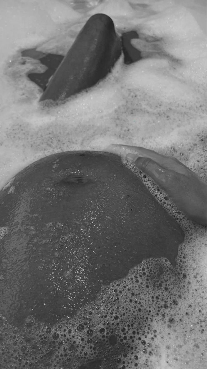 a black and white photo of some rocks in the sand with foamy water on them