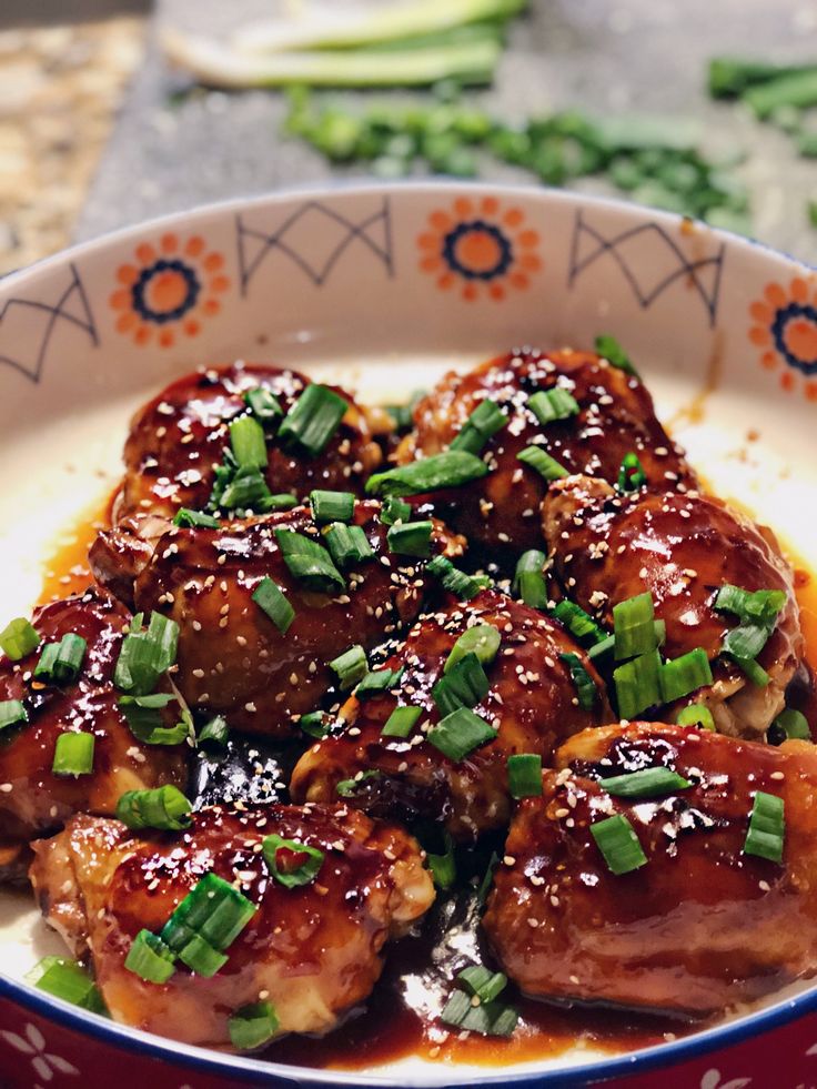 a bowl filled with meat covered in sauce and green onions