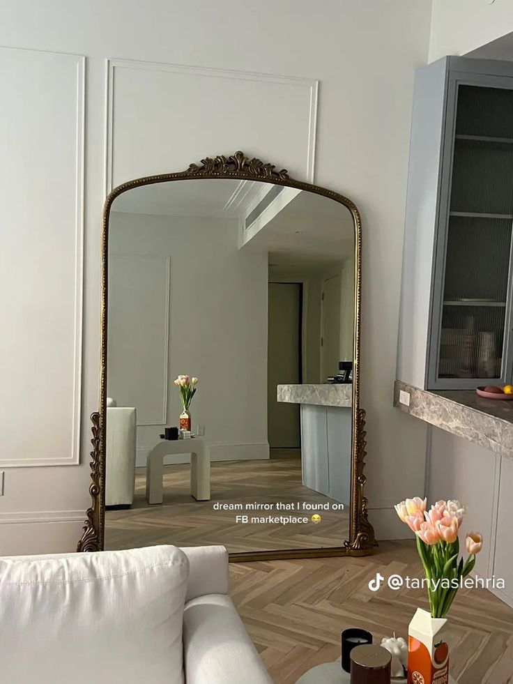 a mirror sitting on top of a white couch in a living room next to a table