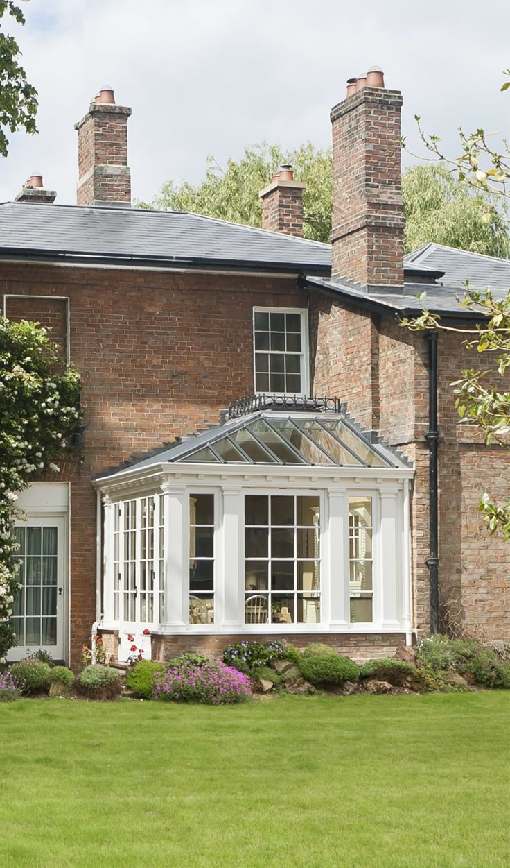 a large brick house with white trim on the roof and windows, surrounded by lush green grass