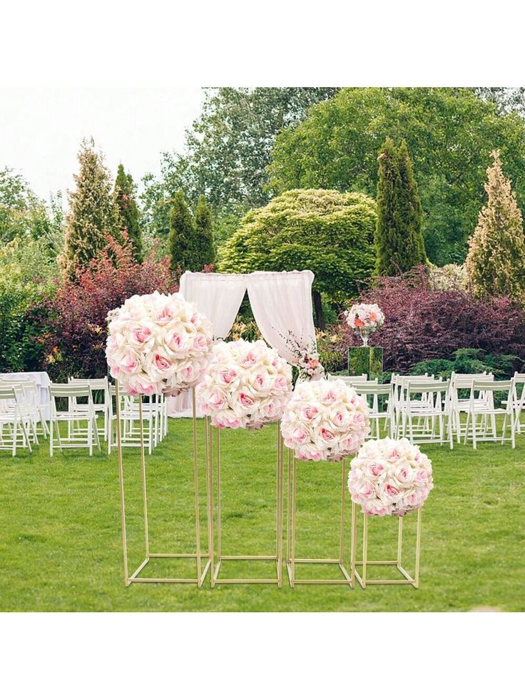 wedding ceremony setup with white chairs and pink flowers on the grass at an outdoor venue