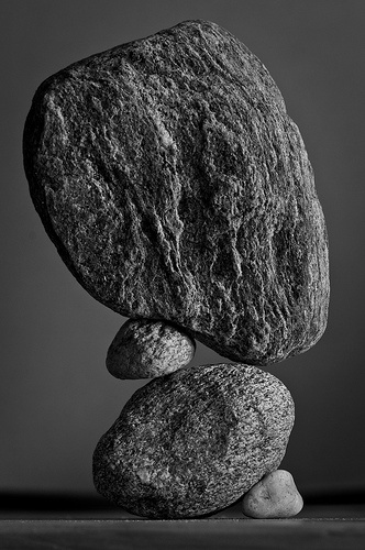 black and white photograph of rocks stacked on top of each other in front of a gray background