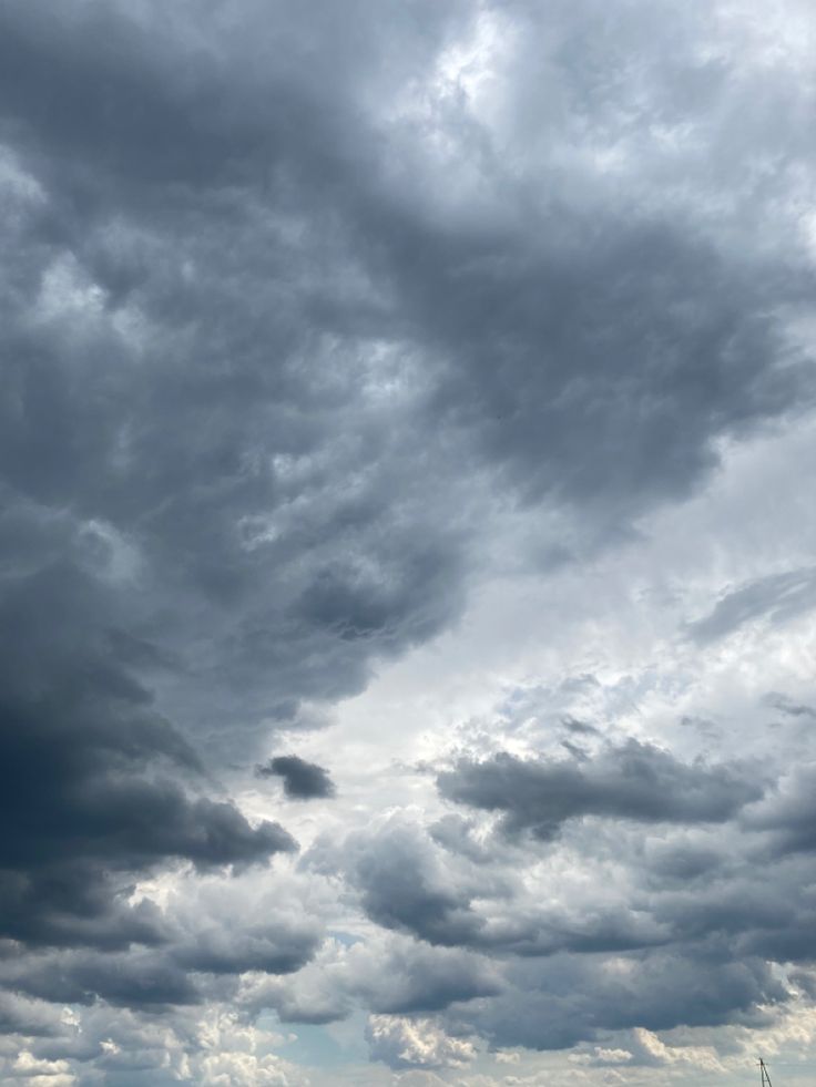 the sky is filled with dark clouds and green grass