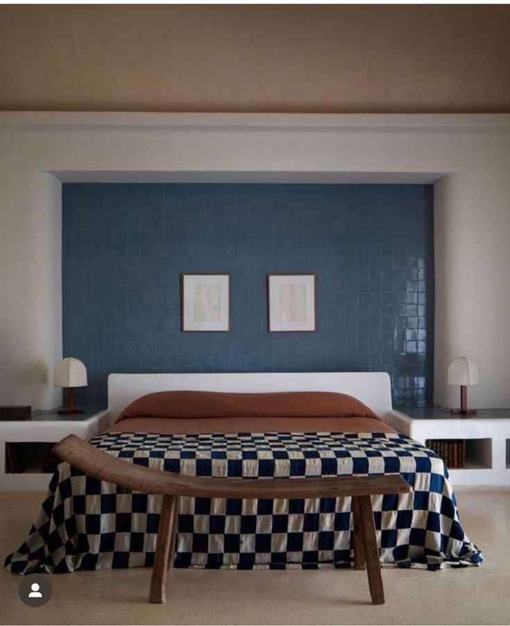 a bed with a checkered blanket on top of it next to a wooden bench