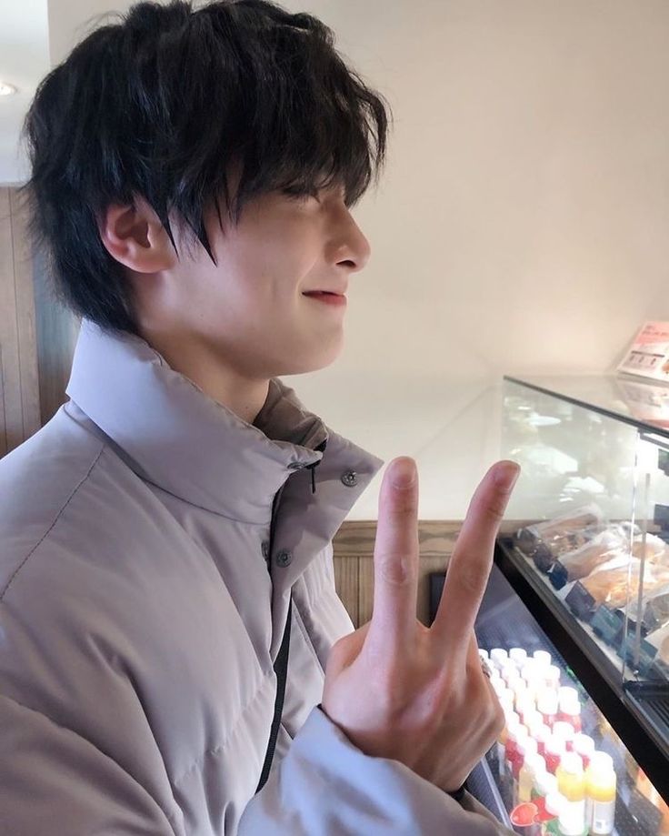 a young man making the vulcan sign in front of a display case full of donuts