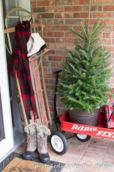 a red wagon with a christmas tree in it and some boots on the front porch