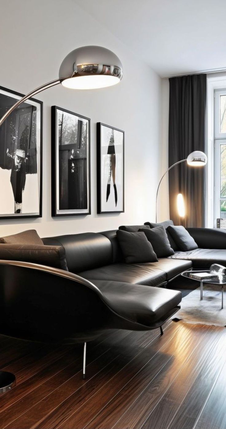 a living room filled with black furniture and pictures on the wall above it's windows