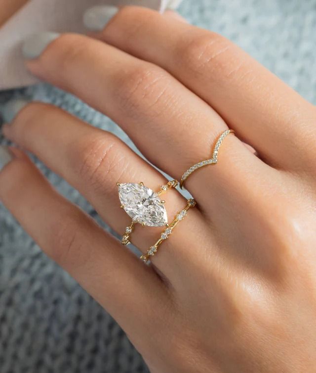 a woman's hand wearing a gold ring with a pear shaped diamond on it