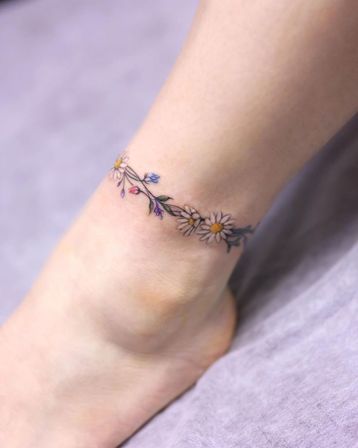 a woman's foot with a flower tattoo on her left ankle and the bottom part of her leg