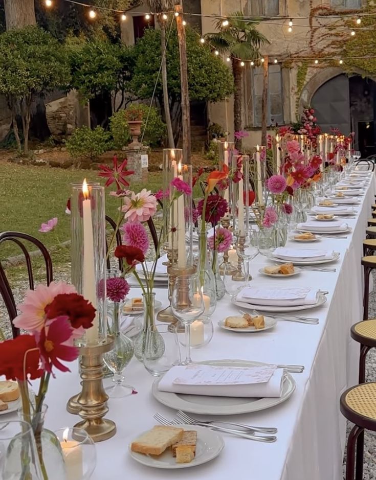 a long table is set up with flowers and candles for an outdoor dinner or party