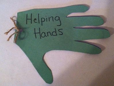 a green hand sign that says helping hands on the side of a white table with a string attached to it