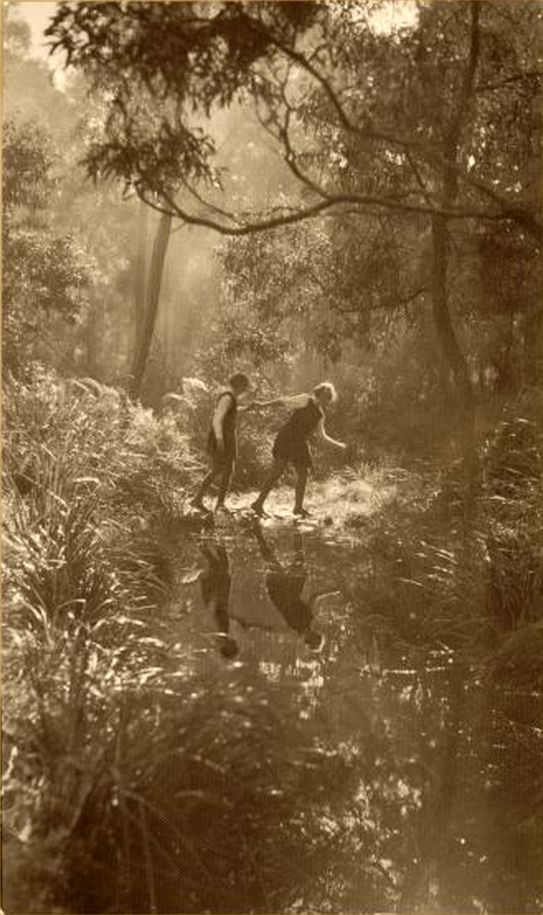 an old photo of two people walking in the woods