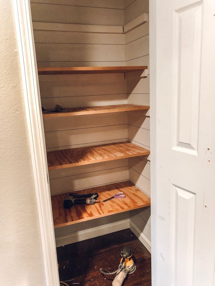 an empty closet with shelves and tools on the floor