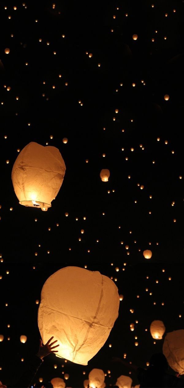 many paper lanterns floating in the air at night