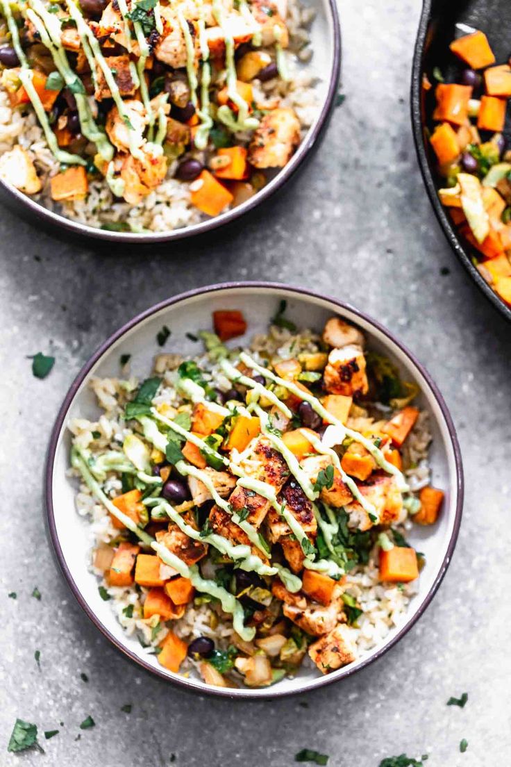 three bowls filled with rice and vegetables on top of a table