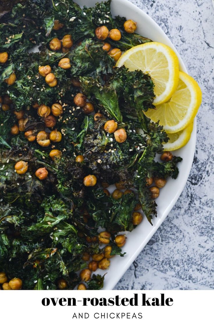 a white plate topped with kale and chickpeas next to lemon wedges