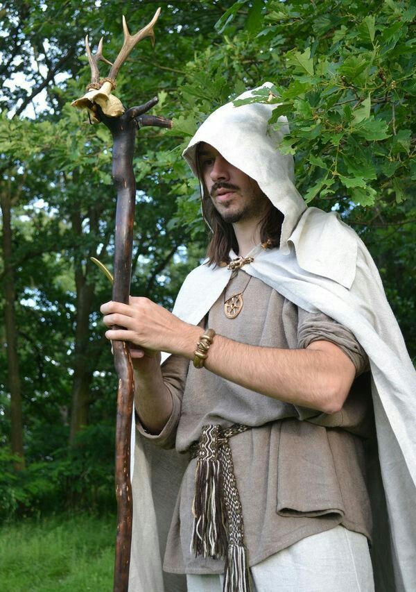 a man dressed in medieval clothing holding a stick with deer antlers on it's head