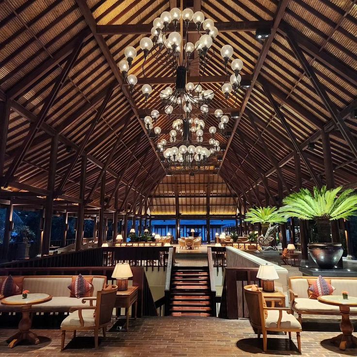 the inside of a restaurant with wooden tables and chandeliers hanging from the ceiling