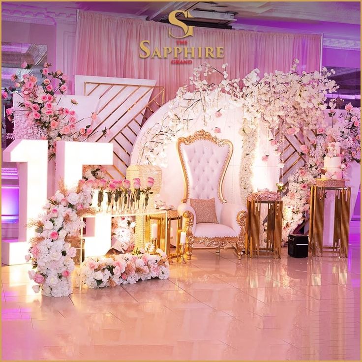 the stage is decorated with pink flowers and gold furniture for an elegant wedding or special event