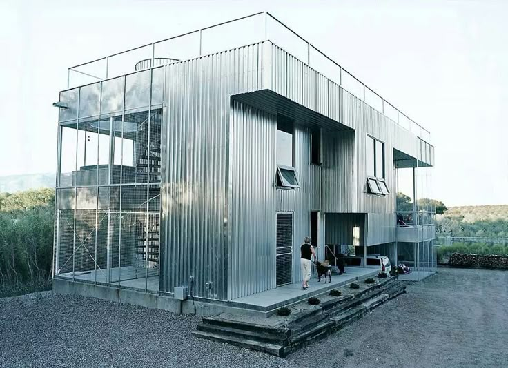 a woman and her dog are standing in front of a metal building that is made out of corrugated