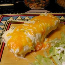 an enchilada on a cutting board with lettuce and sour cream