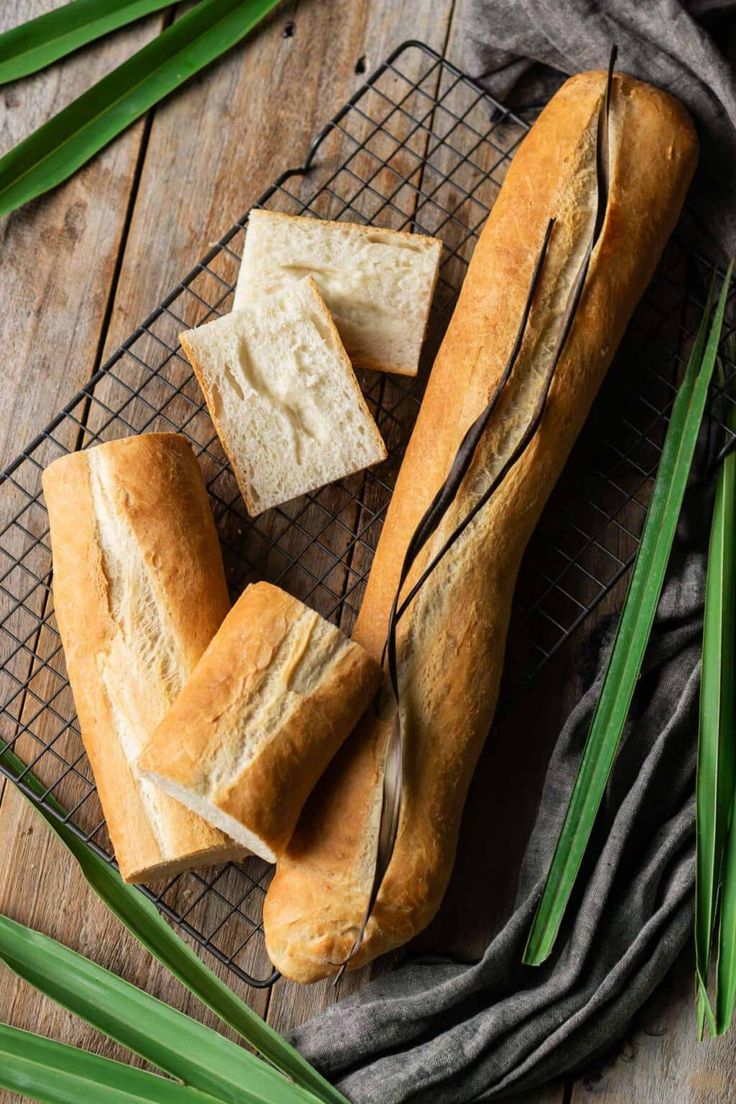 a loaf of bread sitting on top of a cooling rack next to some green leaves