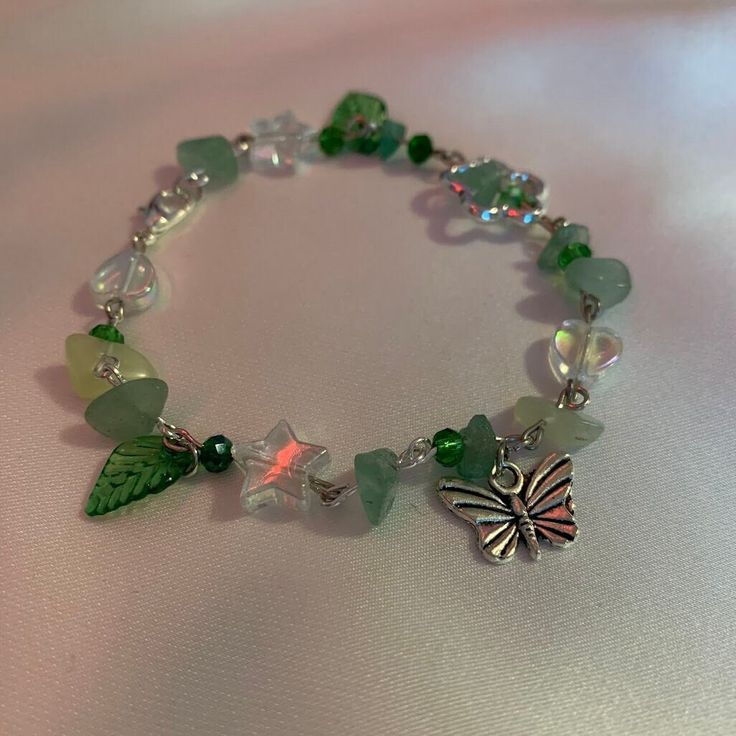 a bracelet with green and white glass beads on it's side, featuring a butterfly