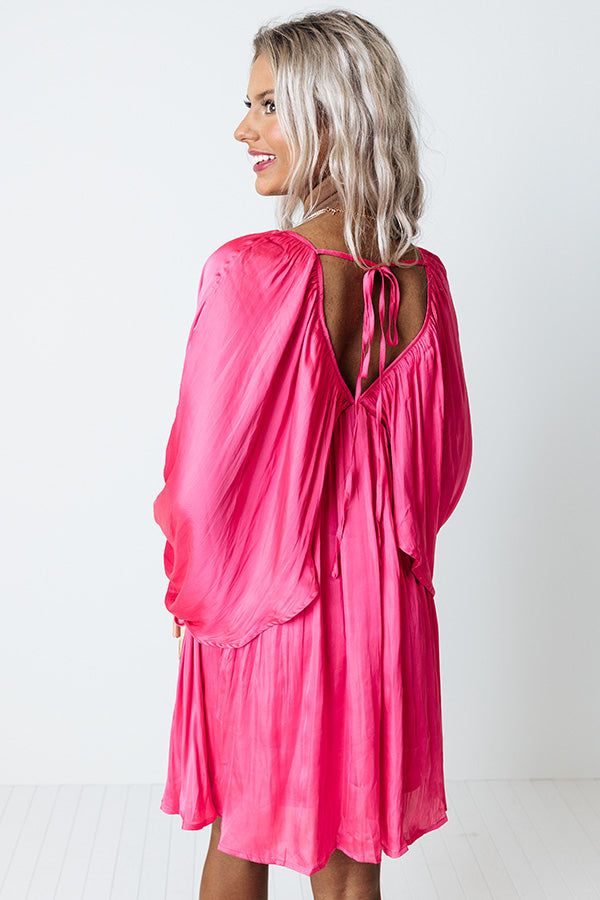 You will be impeccably dressed when you wear this chic pink dress featuring ultra lightweight flowy satin material, a draped overlaid bodice that cascades into long oversized bat wing sleeves with high underarm slits and elastic band cuffs, a deep v-cut neckline and upper back with a tie closure, and an ultra relaxed silhouette that falls into an uneven mid-thigh length hemline!                                   Measurements S variant has  a Bust of 32",  a Hip of 38",  a Length of 33",  a Sleev Feminine Silk Dress With Draped Sleeves, Chic Ruched Satin Dress For Brunch, Spring Draped Satin Dress, Chic Pink Ruched Satin Dress, Pink Satin Mini Dress With Ruched Bodice, Casual Pink Midi Dress With Tie Back, Satin Flowy Dress For Party, Pink Feminine Dress With Draped Sleeves, Satin Party Dress With Flowy Skirt