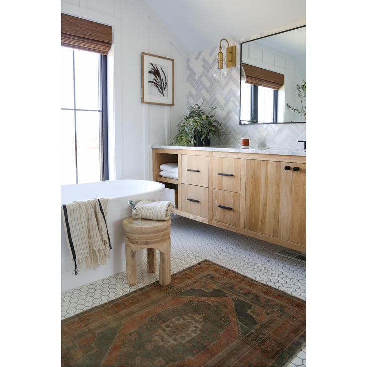 a bath room with a tub a mirror and a rug on the floor in front of it