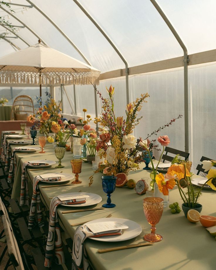 a long table set with plates and vases filled with flowers on top of it