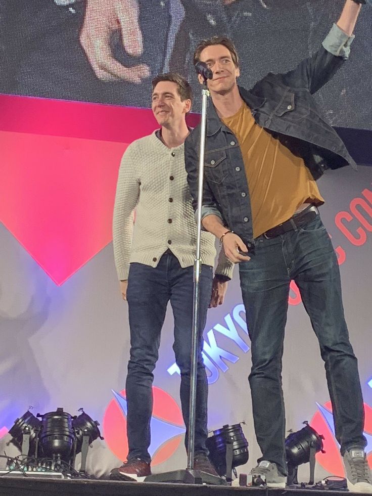 two men standing on stage with microphones in their hands