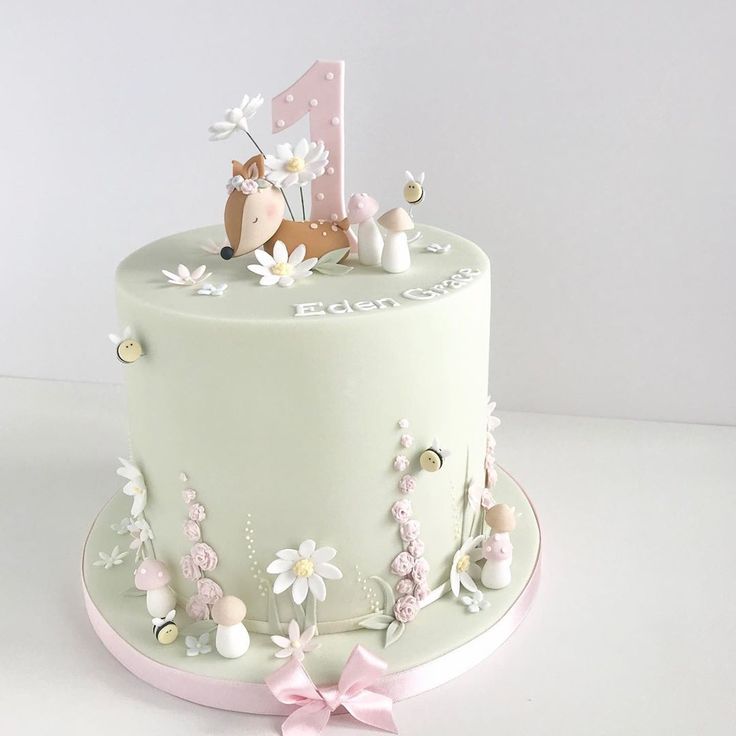 a white cake decorated with flowers and a deer on top