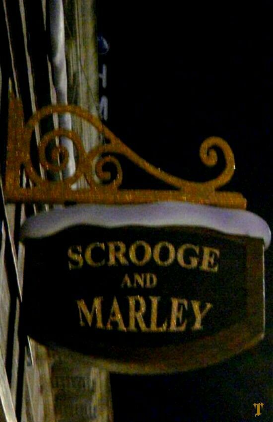 the sign for scrooge and marley is lit up at night