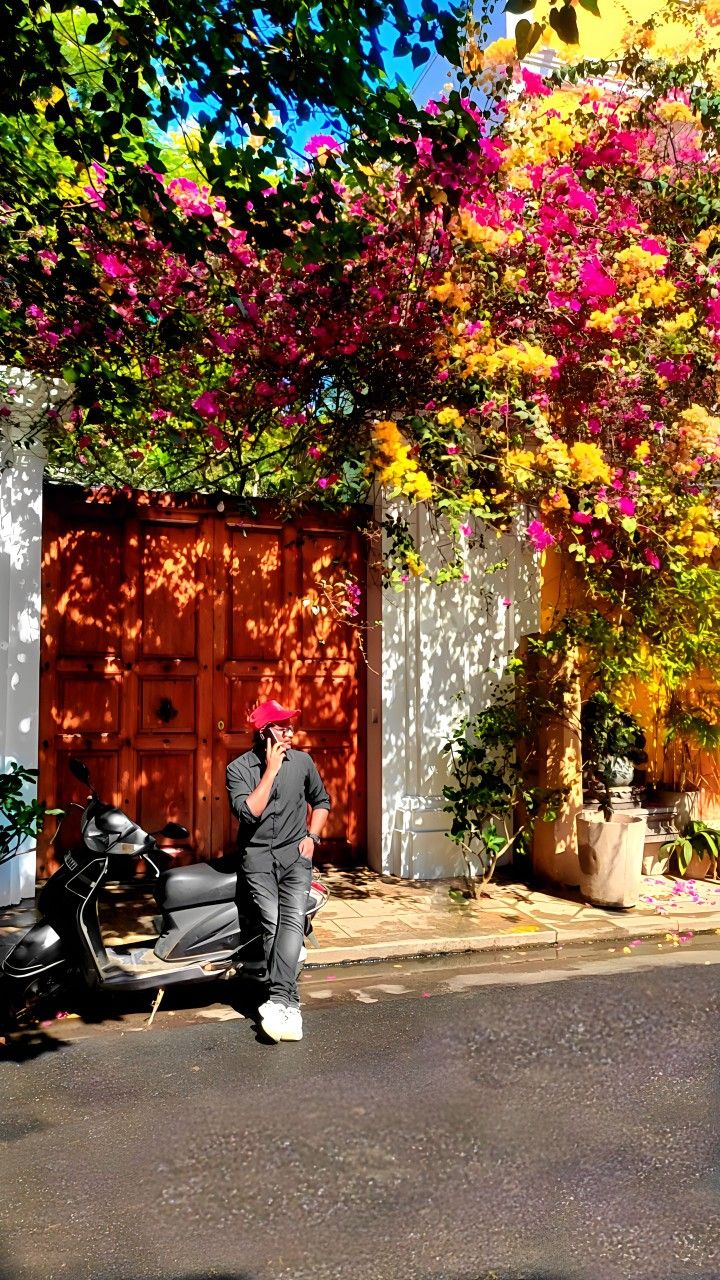 a man standing next to a parked motorcycle in front of a tree with flowers on it