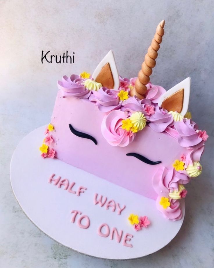 a cake shaped like a unicorn with flowers and a horn on top that says half way to one