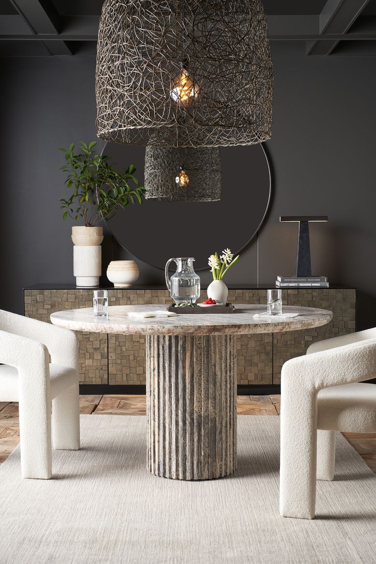 a dining room table with two chairs and a round mirror on the wall above it