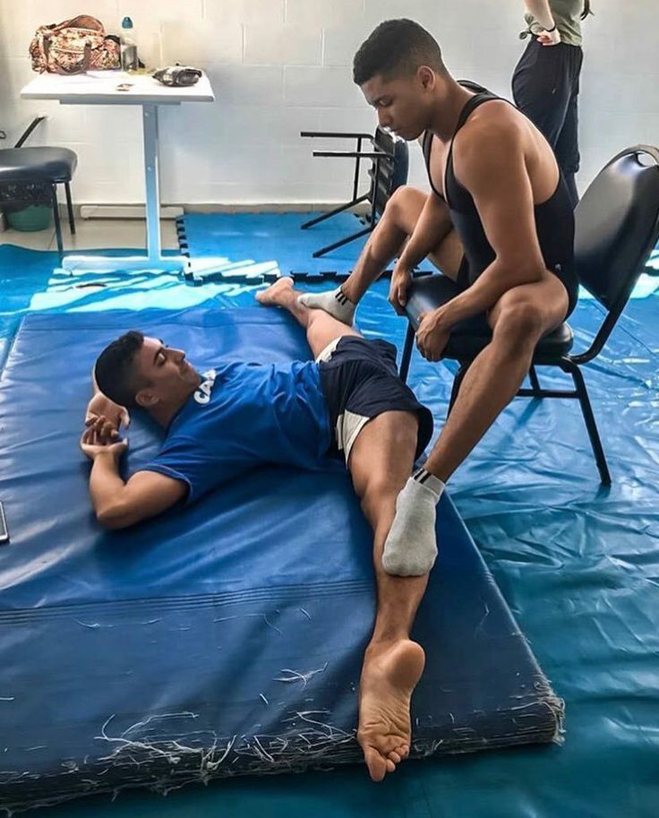 two men sitting on top of a blue mat