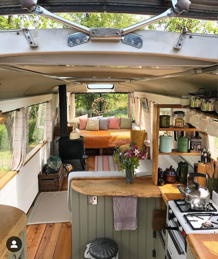 the inside of a camper with wood flooring and kitchen counter tops, stove top oven