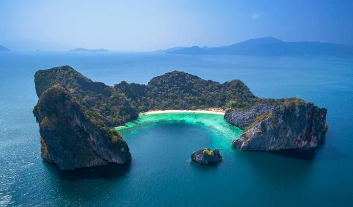 an island in the middle of water surrounded by large rocks and small islands with white sand