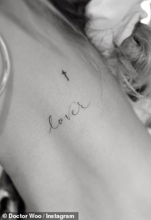 the back of a woman's shoulder with a cross and word love tattooed on it