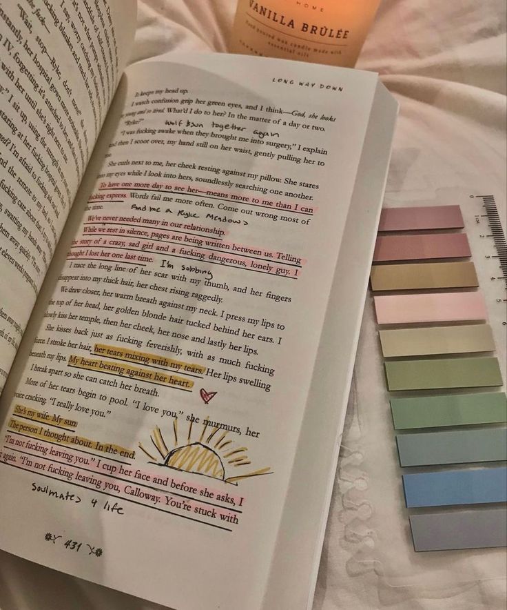 an open book sitting on top of a bed next to a bottle of alcohol and color swatches