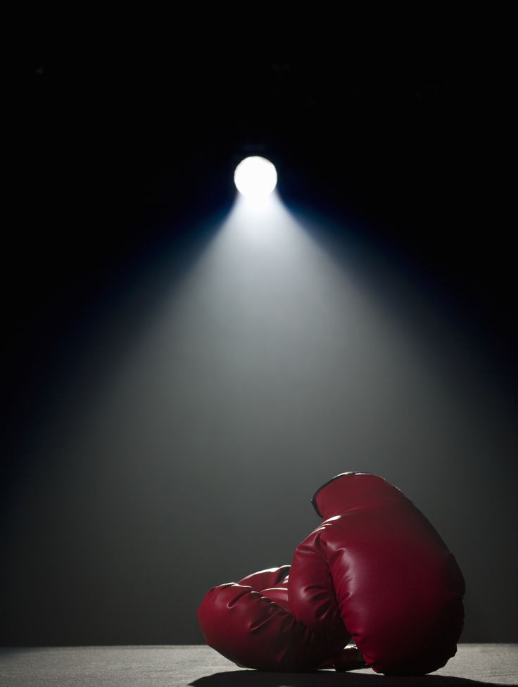 a pair of red boxing gloves sitting on the ground in front of a spotlight light