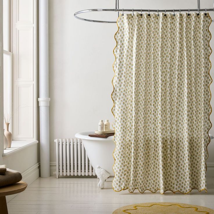 a bathroom with a bathtub, shower curtain and rug on the floor in front of it